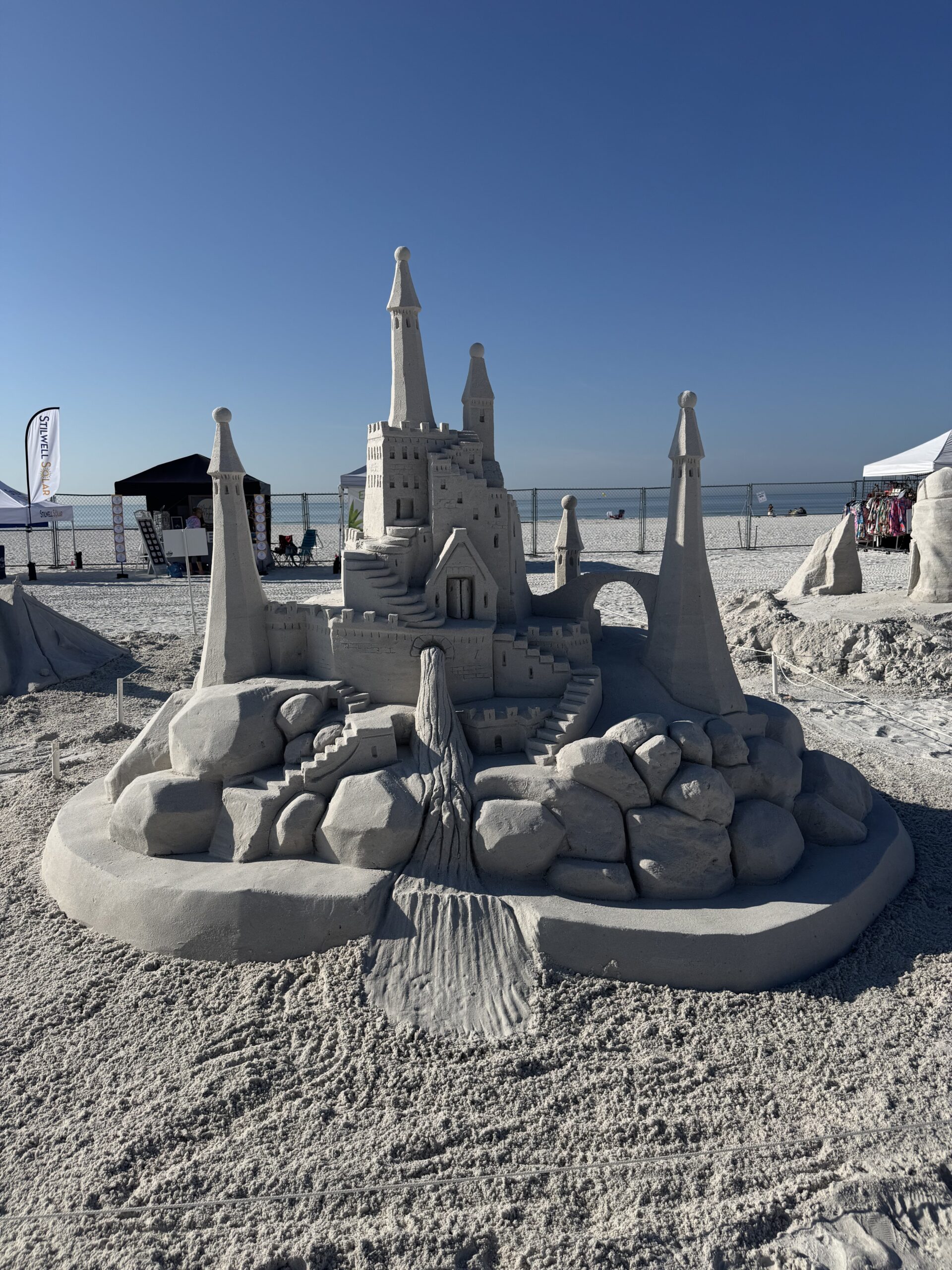 Detailed sandcastle sculpture with towers, bridges, and textures at a beachside competition.