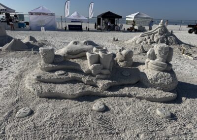 Sand sculpture of sea creatures and ocean floor at beach event.